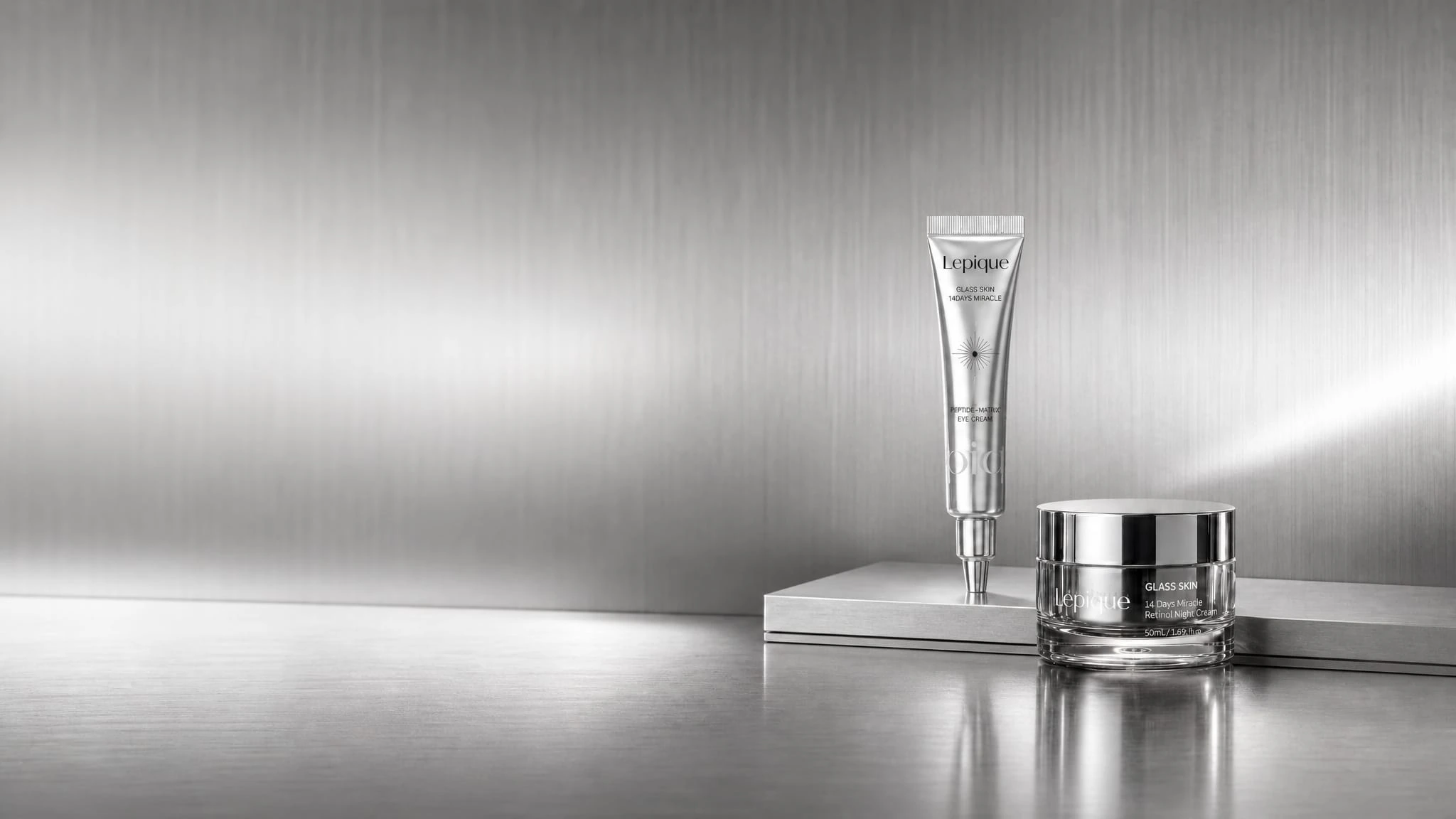 Lepique Glass Skin night cream and peptide eye cream on a silver reflective set